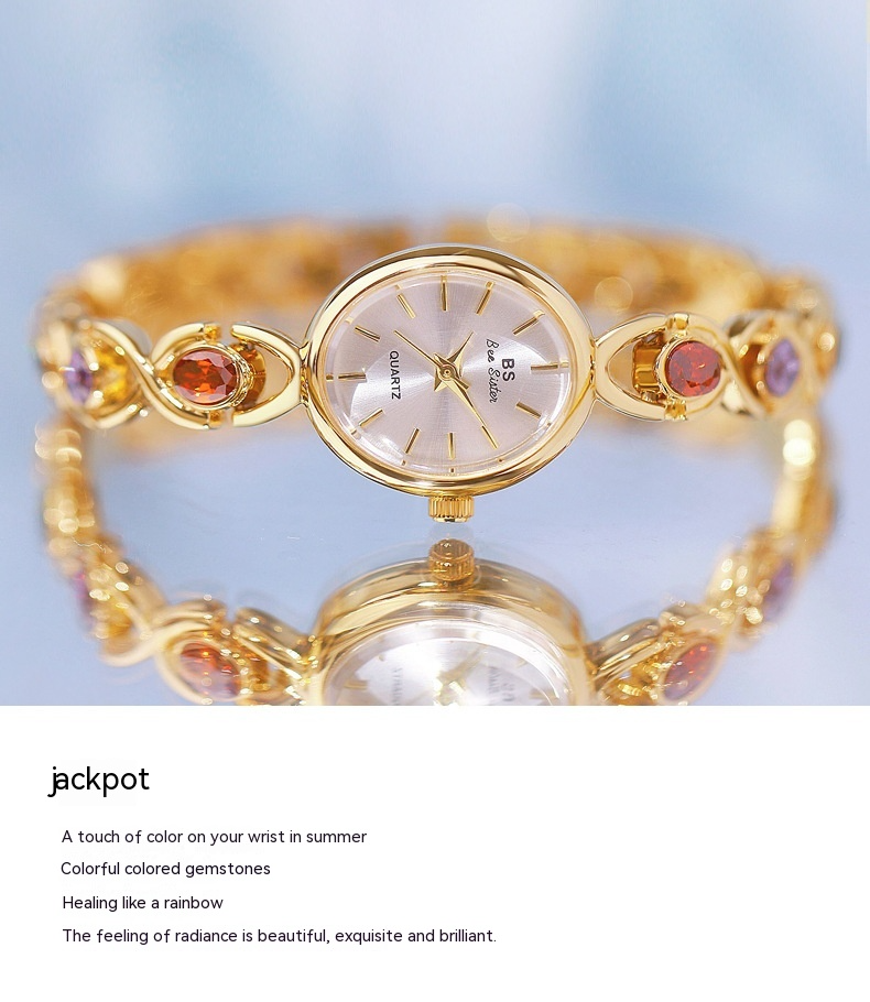 Reloj de lujo de estilo antiguo con gemas ovaladas de colores y luz arcoíris