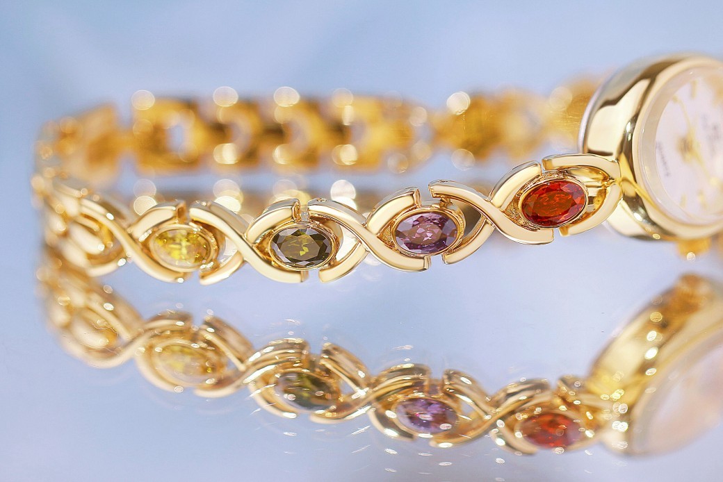 Reloj de lujo de estilo antiguo con gemas ovaladas de colores y luz arcoíris