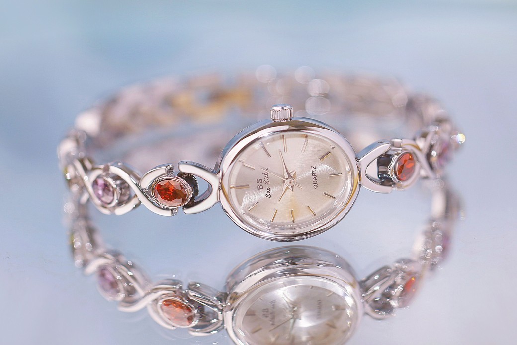 Reloj de lujo de estilo antiguo con gemas ovaladas de colores y luz arcoíris