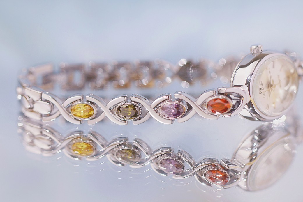 Reloj de lujo de estilo antiguo con gemas ovaladas de colores y luz arcoíris