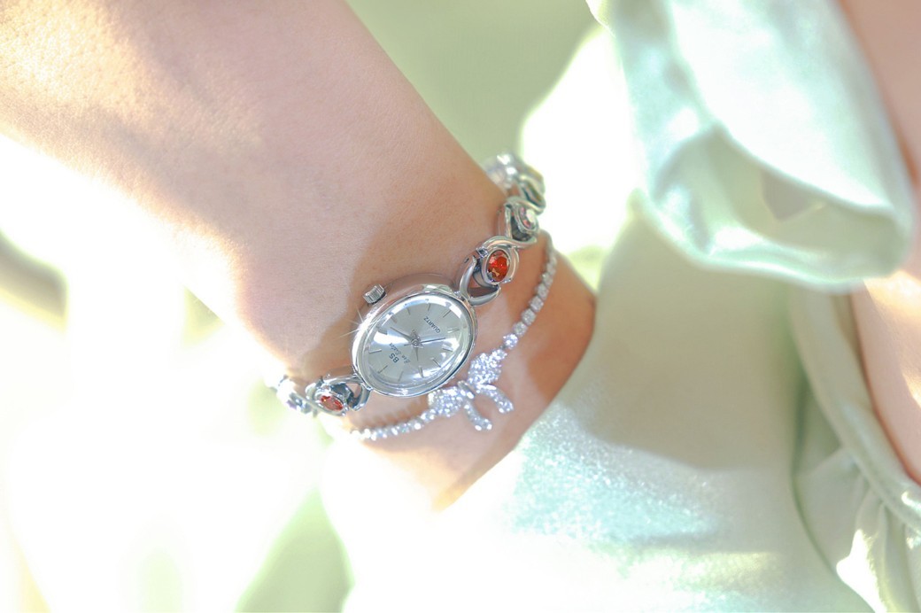 Reloj de lujo de estilo antiguo con gemas ovaladas de colores y luz arcoíris