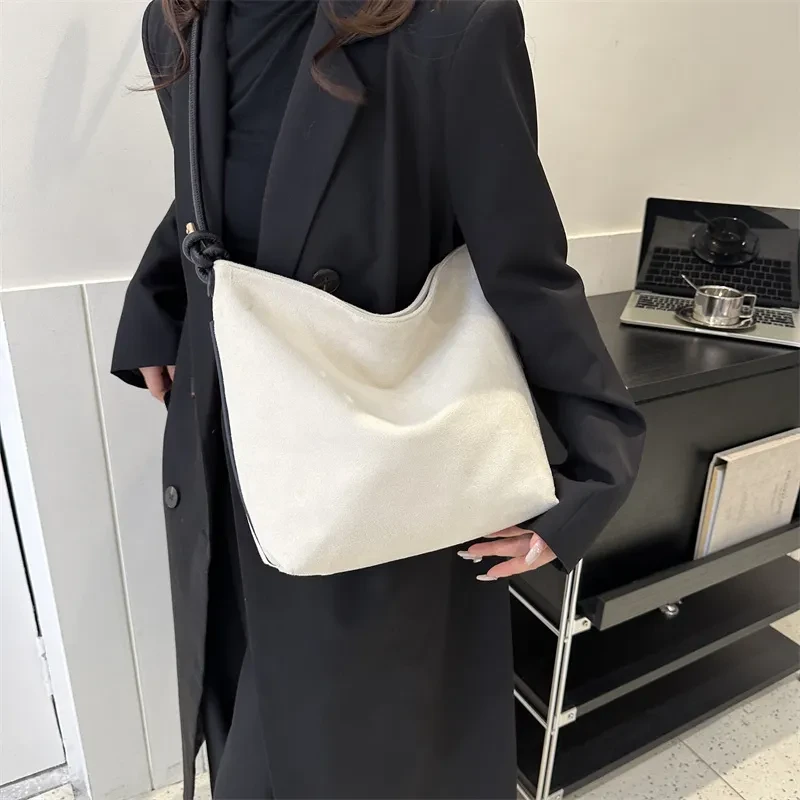 Bolso de mano informal de gran capacidad, de ante esmerilado, a la moda, para llevar al hombro o debajo del brazo.