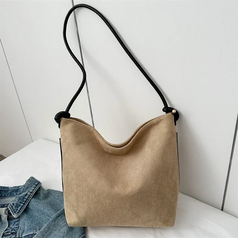 Bolso de mano informal de gran capacidad, de ante esmerilado, a la moda, para llevar al hombro o debajo del brazo.