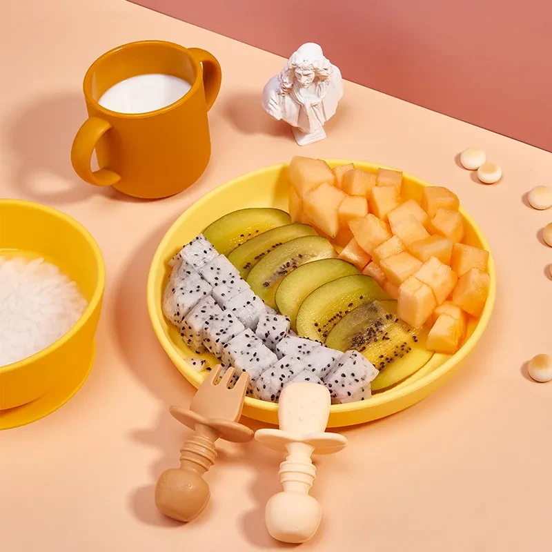 Juego de cubiertos para niños con cuchara de silicona y recipiente anticaídas para llenar con agua.
