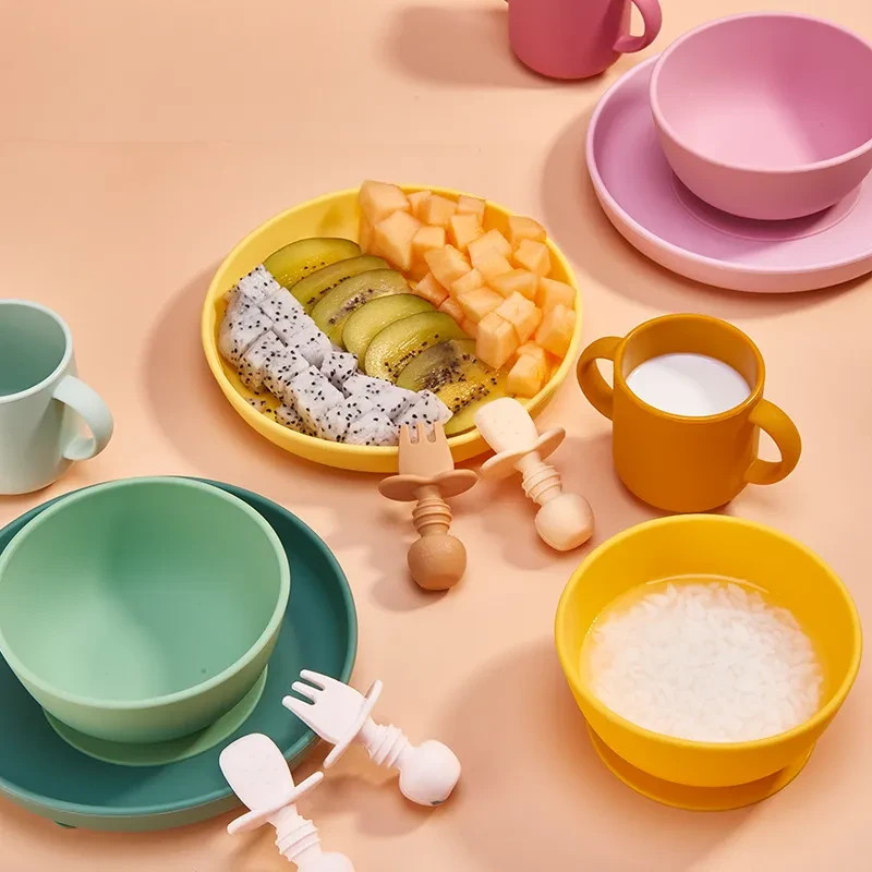 Juego de cubiertos para niños con cuchara de silicona y recipiente anticaídas para llenar con agua.